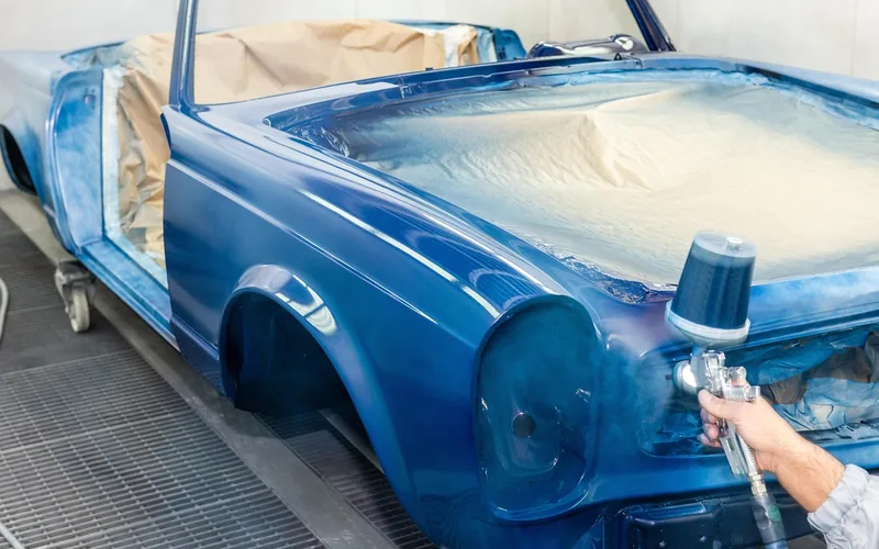 painter using a spray gun near a parked car, a common cause of paint splatter and overspray painter using a spray gun near a parked car, a common cause of paint splatter and overspray
