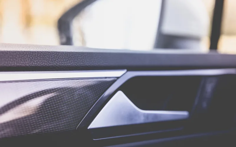 Close-up of a car's driver-side exterior mirror reflecting the road behind it