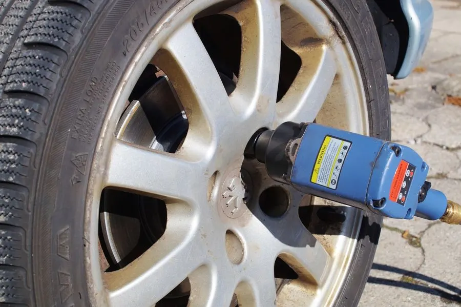 Impact wrench removing a wheel nut from a car wheel