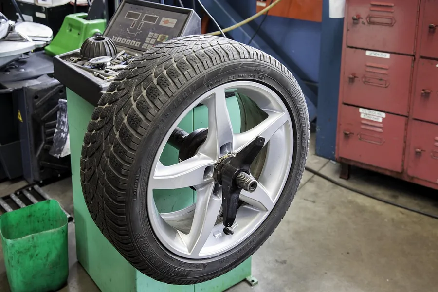 Winter tire and alloy wheel mounted on a tire balancing machine in a car repair shop
