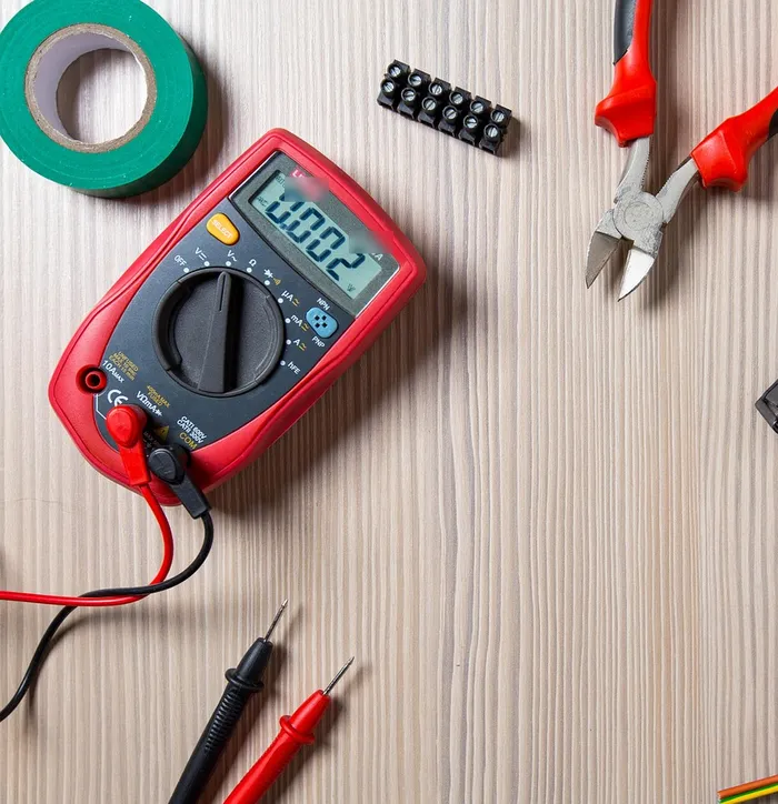 Digital multimeter with red and black test leads on a workbench