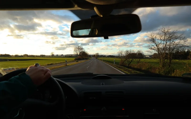 Driver's view of a car's interior rearview mirror while driving on the road