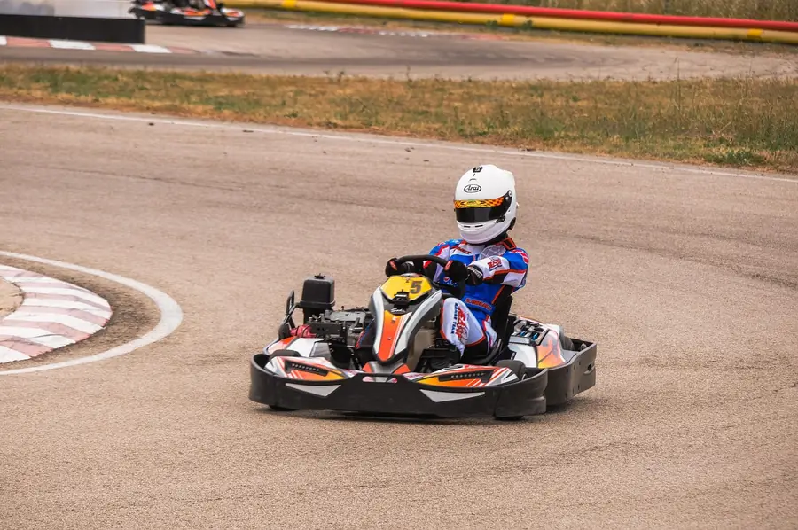Driver in a helmet taking a corner in a go-kart on a paved kart circuit