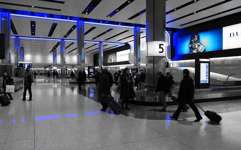 Traveler collecting a suitcase in an airport arrivals baggage claim hall Traveler collecting a suitcase in an airport arrivals baggage claim hall