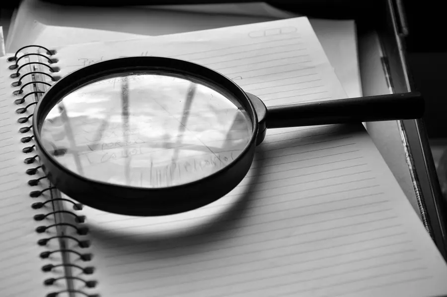 Magnifying glass lying on an open spiral notebook with lined pages