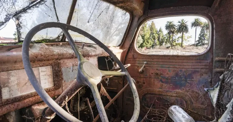 Interior of a weathered old truck cab showing the steering wheel and dashboard