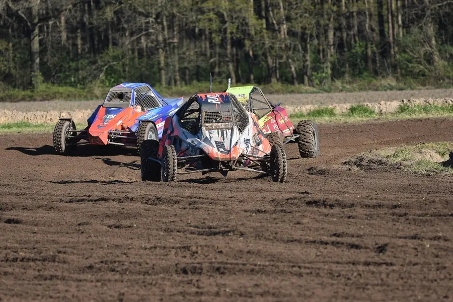 Three open-wheel off-road buggies racing on a dirt course