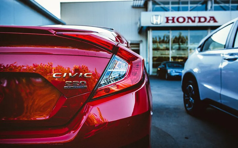 Glossy red Honda parked on a dealership lot Glossy red Honda parked on a dealership lot