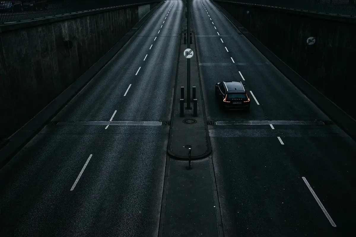 A single car driving on an empty multi-lane road