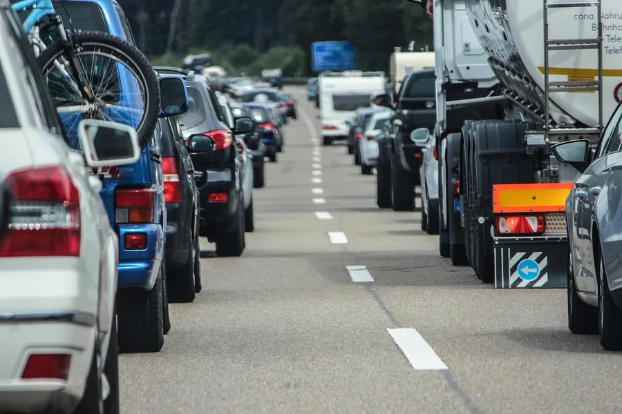 Queue of cars and a tanker truck in slow traffic on a multi-lane road