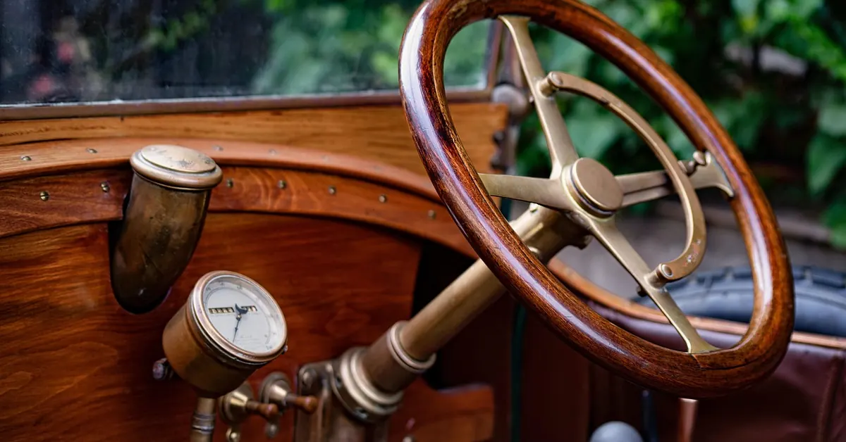 Wooden steering wheel and brass fittings on the dashboard of a vintage car
