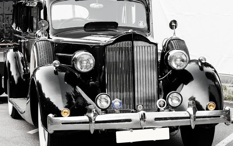 Close-up of a vintage luxury car's polished chrome grille and headlights, typical of 1920s coachbuilt automobiles
