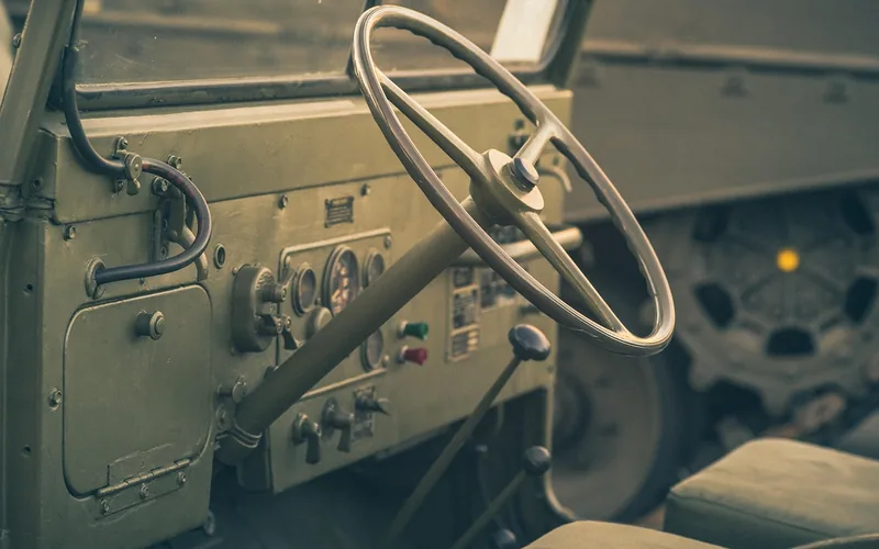 Dashboard and steering wheel of a vintage utility vehicle with round gauges and a thin-rimmed wheel