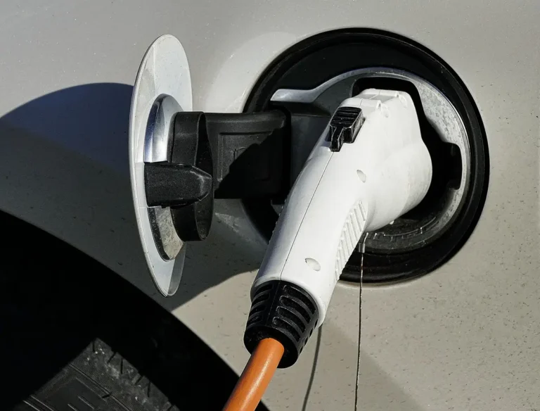 White charging plug connected to the charge port of an electric car