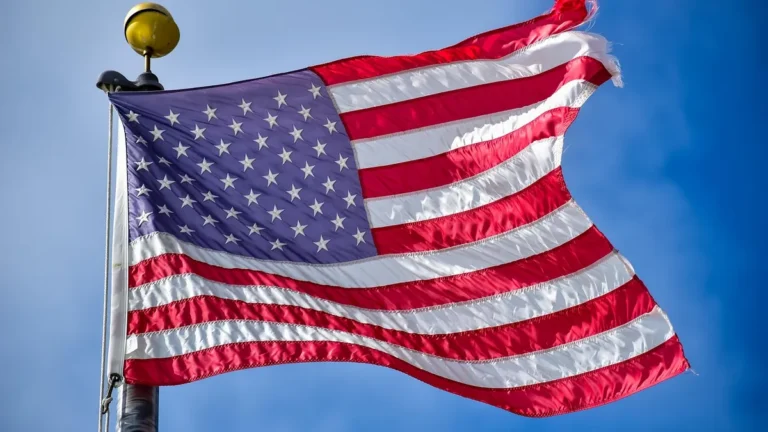 American flag waving on a flagpole against a blue sky