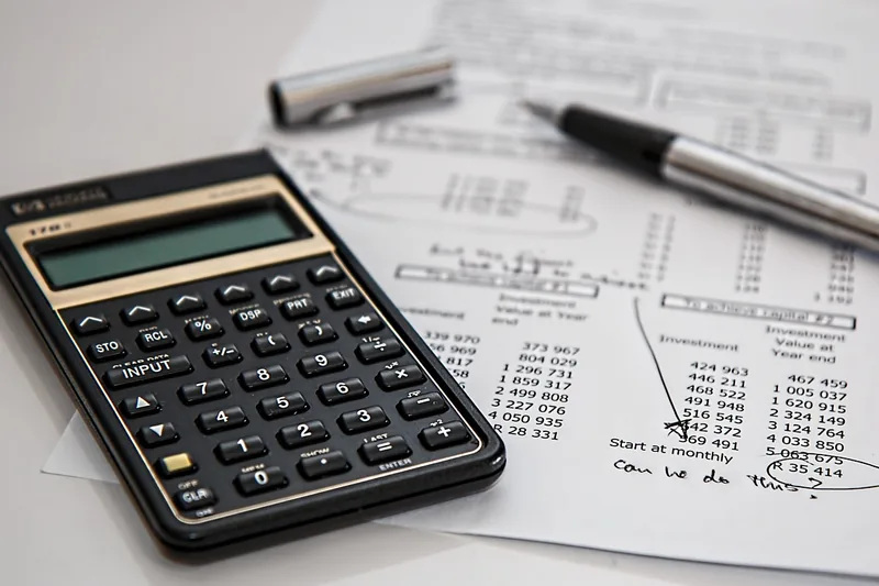 Calculator and pen resting on a printed worksheet of loan payment figures