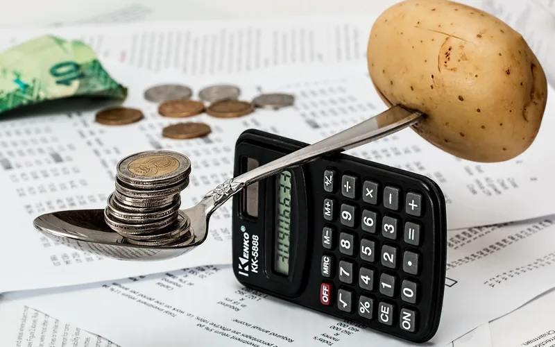 Calculator, coins and a household budget worksheet used to work out a monthly car payment
