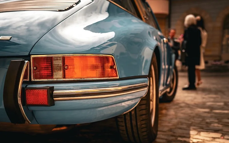 Rear view of a light blue classic sports coupe parked on a cobbled street