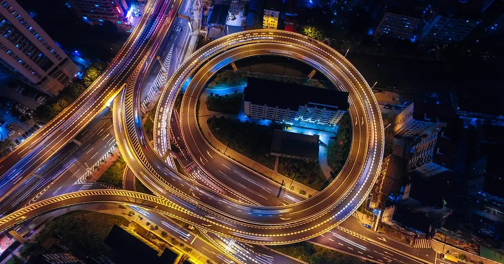 Aerial night view of a city highway interchange with light trails