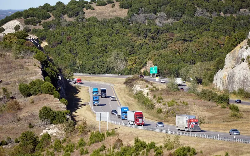 Cars and trucks driving on an Oklahoma interstate highway, representative of vehicle traffic across US states