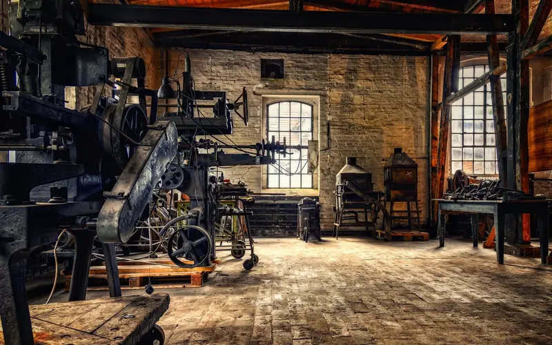 Old brick machine shop with belt-driven machines and a workbench under tall windows