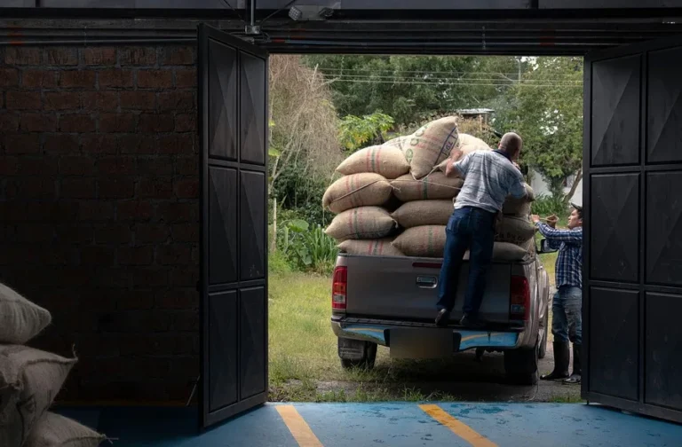 Rear of a pickup truck loaded with sacks at a warehouse door, showing the tailgate