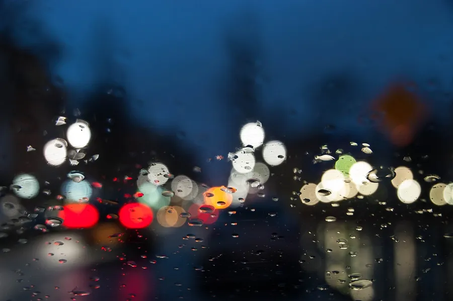 Moisture on a windshield at night blurring the lights of traffic ahead