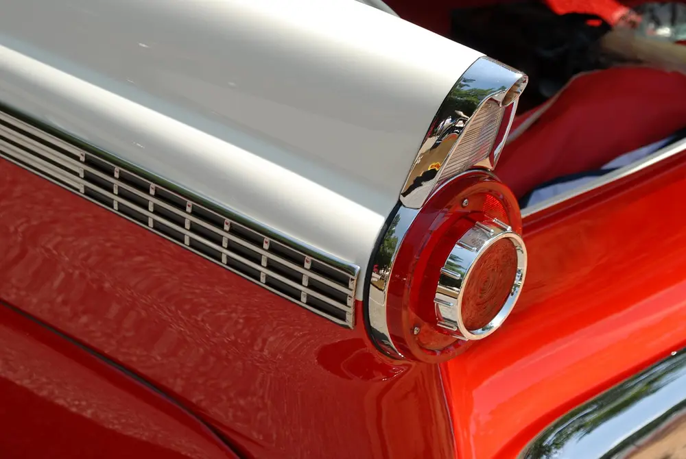 Red and white two-tone tail fin with a chrome tail light on a vintage car