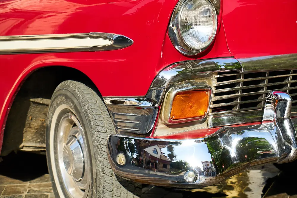 Chrome bumper, headlight and grille corner on a red classic car