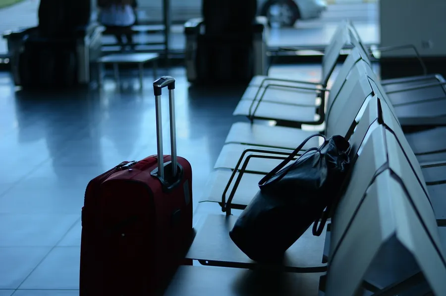 Red suitcase and a black bag beside airport waiting seats