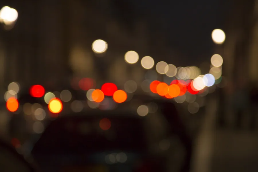 Blurred red and white vehicle lights and street lights on a night street