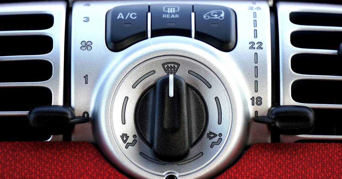 Close-up of a car's HVAC vent and climate control panel with airflow directed by the blower motor