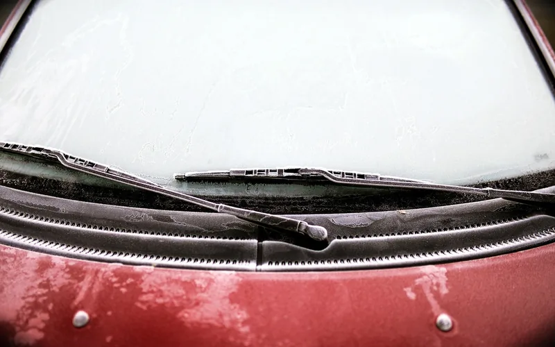 Fogged-up car windshield with condensation blocking the driver's view in winter