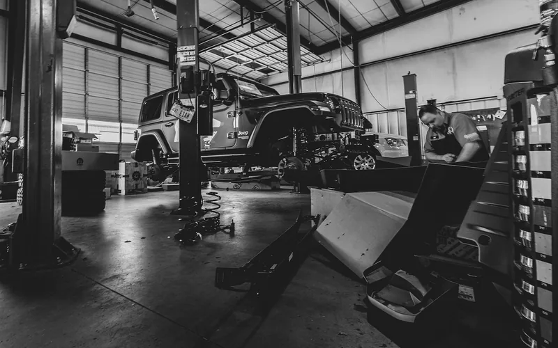 Jeep Wrangler SUV raised on a shop lift for underbody service and tire access