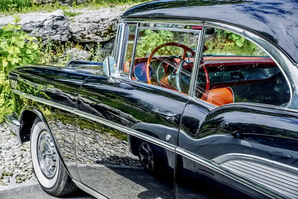 Side view of a black 1950s Chevrolet four-door hardtop with chrome trim and whitewall tires