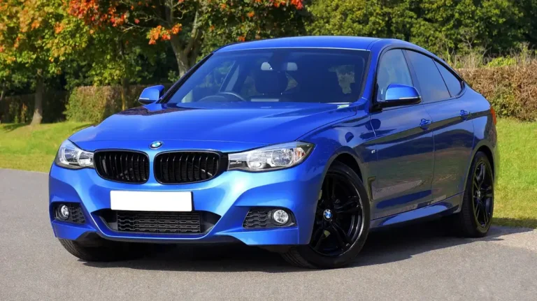 blue four-door car with black wheels parked on a paved road