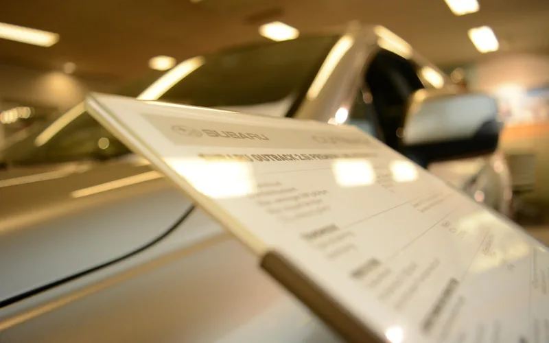 Used car dealership lot with a for-sale price board displayed on a vehicle windshield