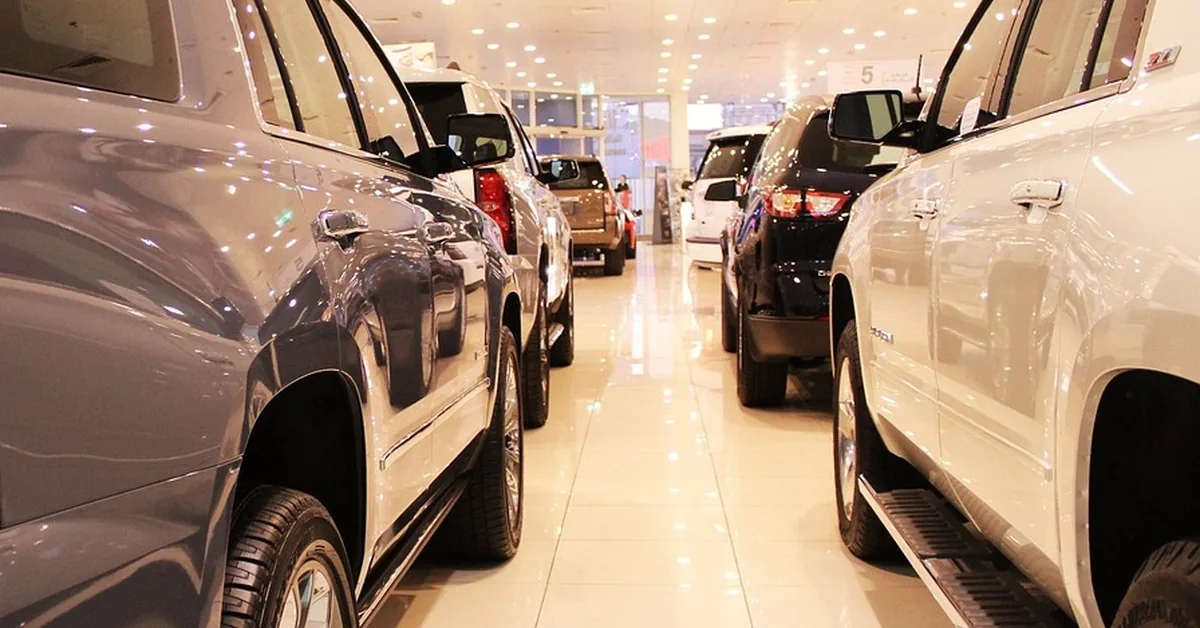 Rows of vehicles parked inside a bright car dealership showroom
