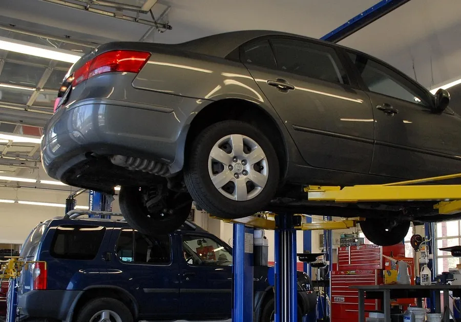 Gray sedan raised on a two-post lift in a service bay