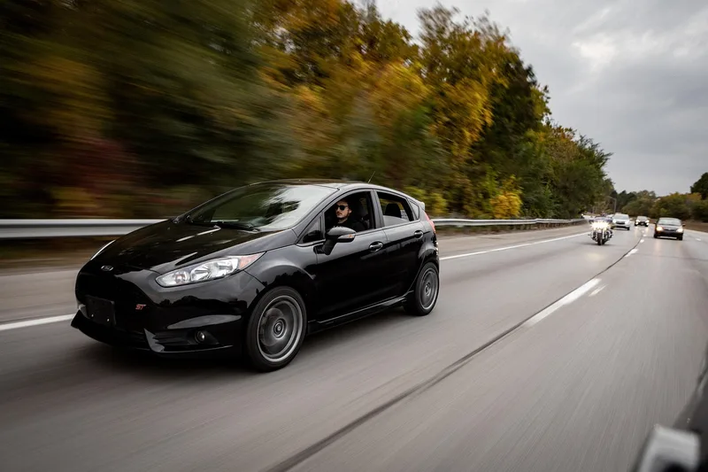 black compact hatchback driving on a highway