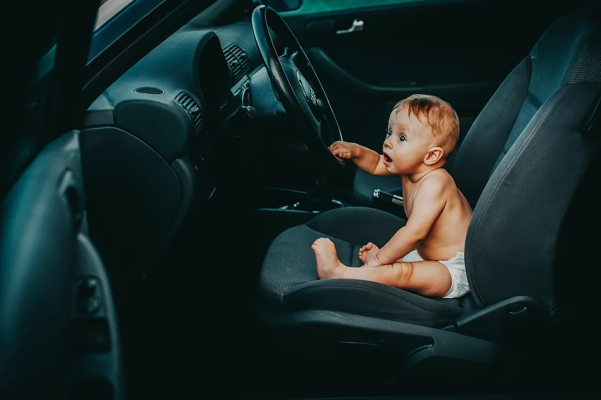 Infant car seat with a five-point harness in the back seat of a car.