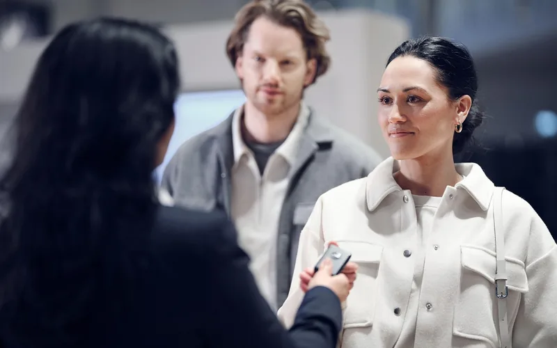 Car salesperson handing over keys while discussing pricing details with a customer