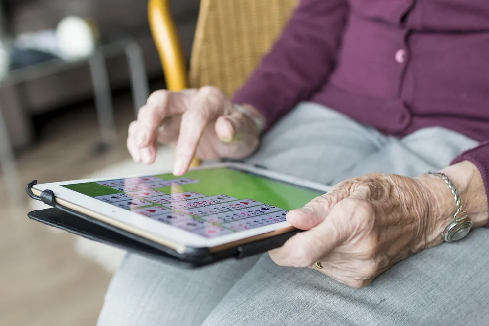 Two hands holding a tablet while one finger touches its screen