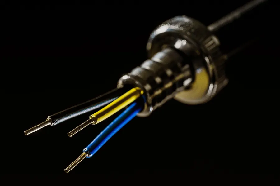 Close-up of a cable with three stripped wire ends in black, yellow and blue insulation