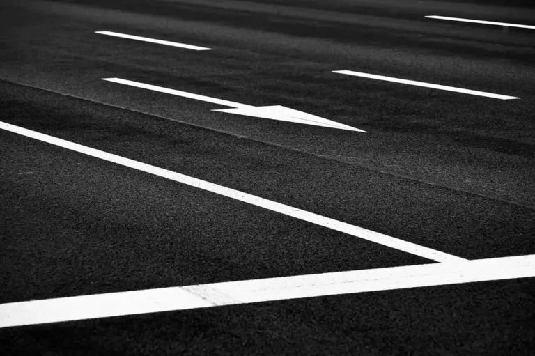 White lane lines and a direction arrow painted on dark asphalt