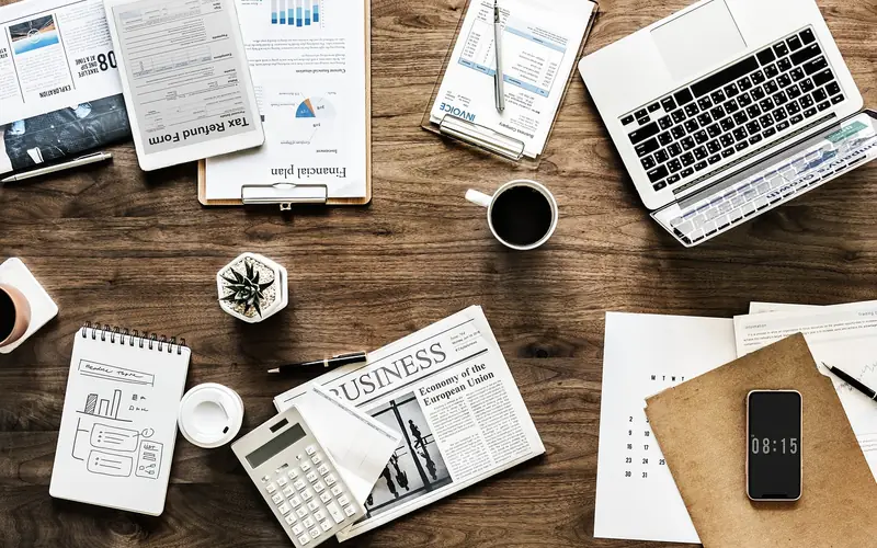 Desk with laptop, notebook, calculator and business paperwork
