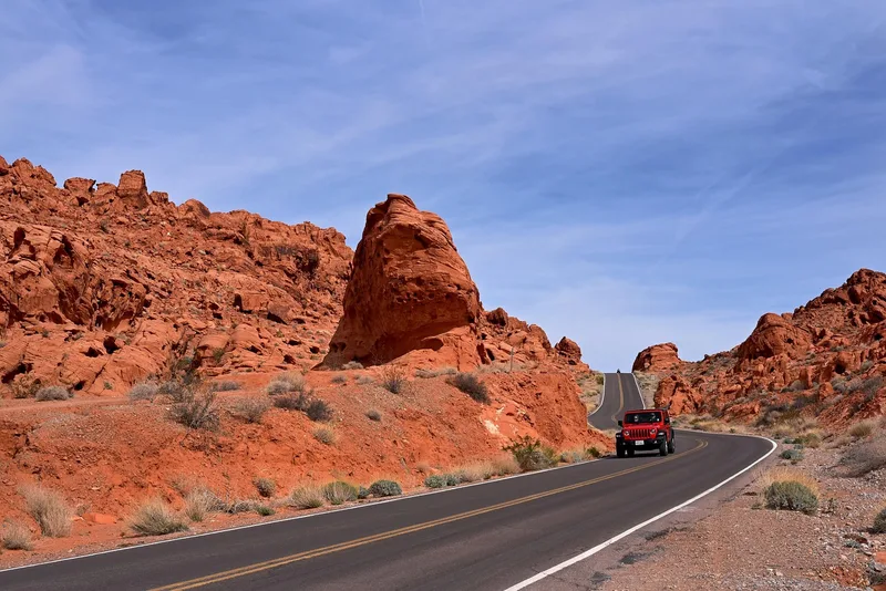 red SUV driving on a winding desert highway