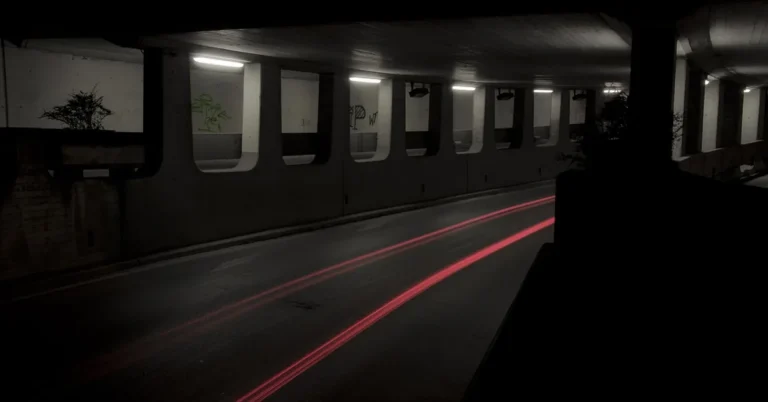 Road underpass at night with red light trails from passing cars
