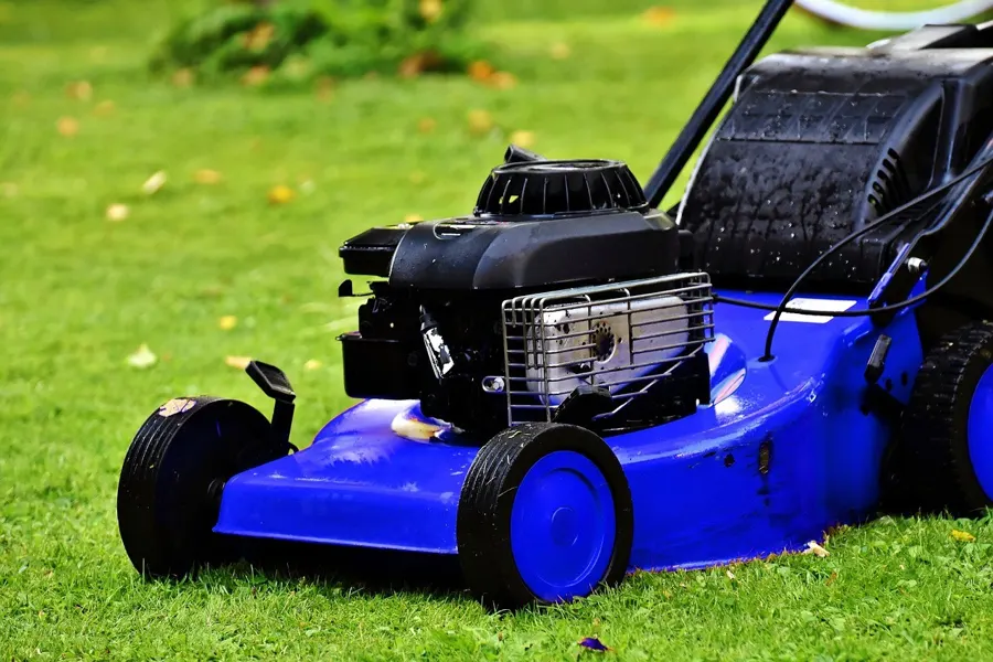 Blue push lawn mower with a small gasoline engine on grass