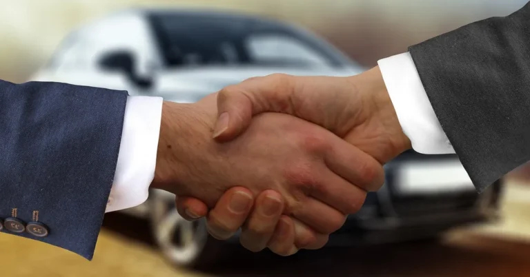 Car buyer shaking hands with a dealer after agreeing on a down payment